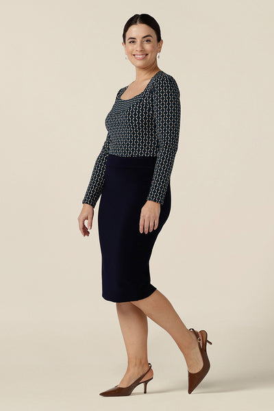 A good work top for corporate capsule wardrobes, this long sleeve top has a squared scoop neckline and blue and white geometric print. Made in Australia, this office wear top is worn with a knee-length navy pencil skirt and is ready to shop in sizes 8 to 24.