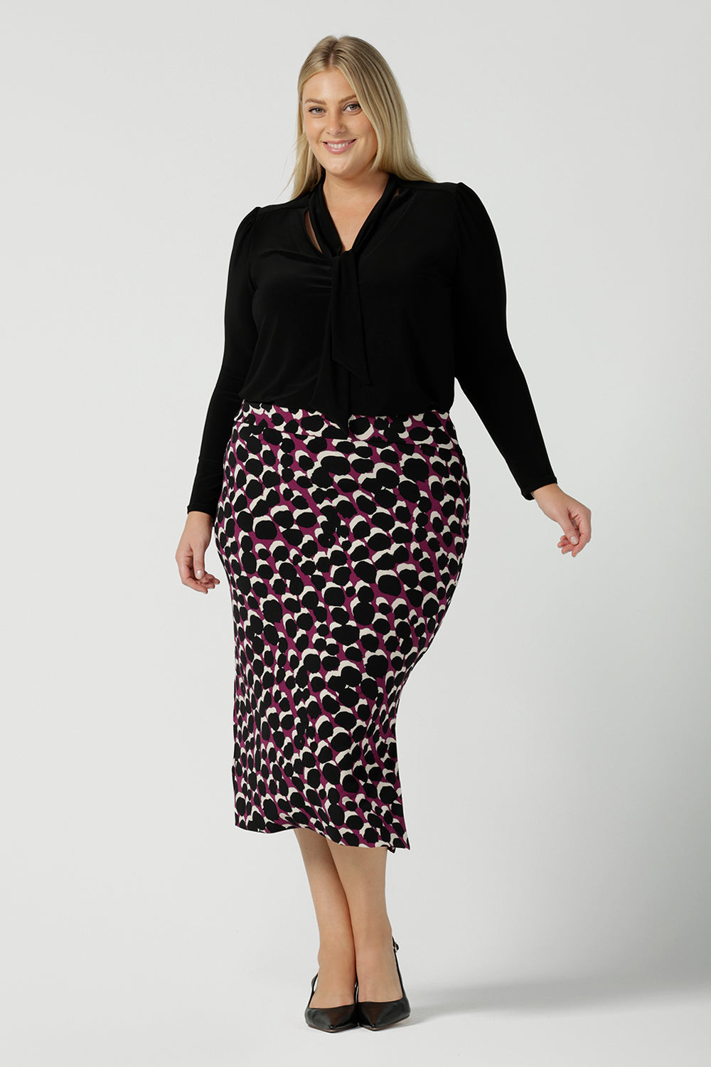 A size 18 woman wears the Thom top in Black a tie neck top with a V-neckline. Made in comfortable jersey have and made in Australia for women size 8 - 24.