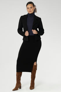 The Andi Midi Skirt in Black is designed in a sophisticated mid-calf length with a flattering side-split, making it perfect for both work and events. Crafted as a double-layer tube skirt, it features a soft folded waistband and a comfortable pull-on style, combining elegance with ease of wear.