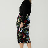 A size 10 woman wears the Boronia Midi Skirt back with a black tie neck top. Made in Australia for women size 8 - 24.