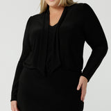 Size 18 woman wears the Thom top in Black a tie neck top with a V-neckline. Made in comfortable jersey have and made in Australia for women size 8 - 24. 