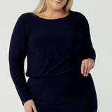 Size 18 woman wears the Navy Mason top in Navy dry touch jersey. Made in Australia for women size 8 -24. Long sleeve and round neckline. Styled back with the Andi skirt in navy. 