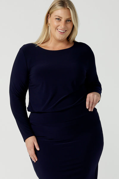 Size 18 woman wears the Navy Mason top in Navy dry touch jersey. Made in Australia for women size 8 -24. Long sleeve and round neckline. Styled back with the Andi skirt in navy. 