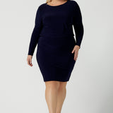 Size 18 woman wears the Navy Mason top in Navy dry touch jersey. Made in Australia for women size 8 -24. Long sleeve and round neckline. Styled back with the Andi skirt in navy.