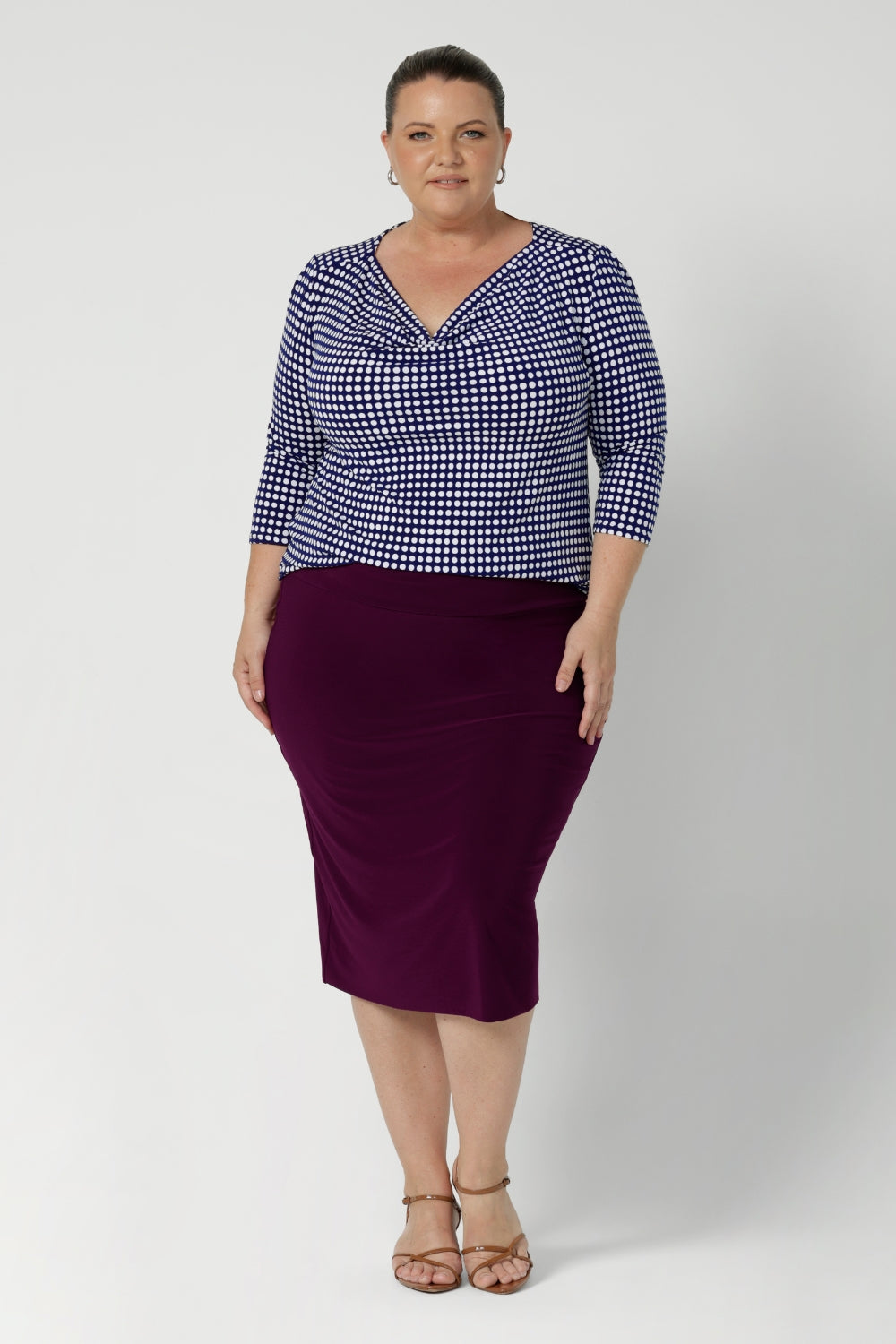 A size 18 woman wears the Andi skirt in Magenta. A made in Australia skirt styled back with Kyrie Top in Polka Dot. Size 8 - 24.