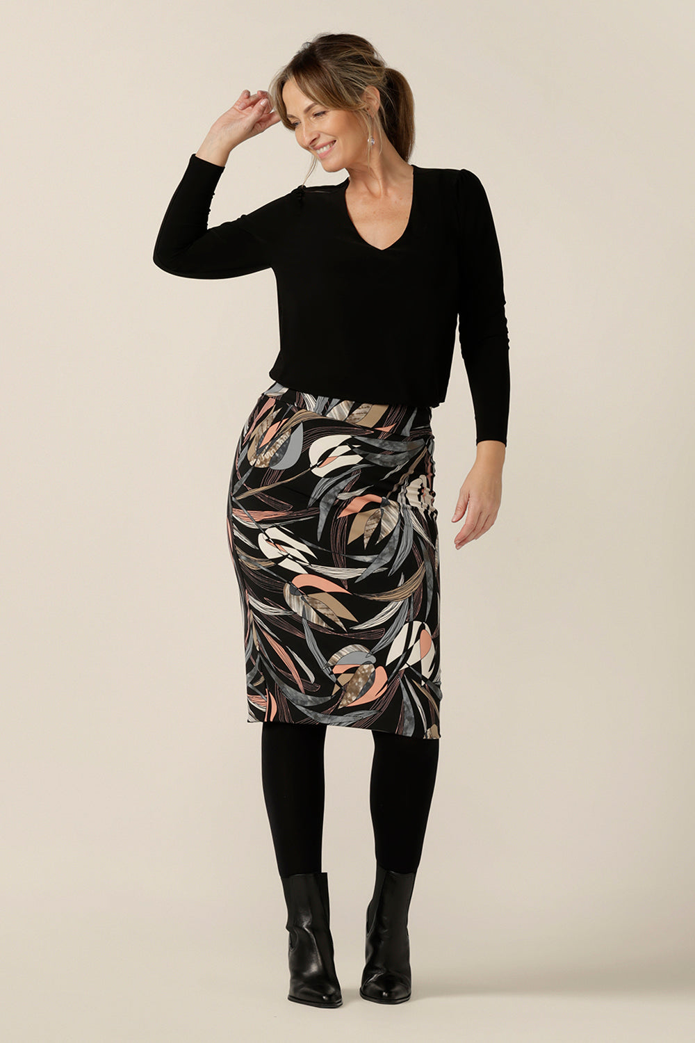 A woman wears a knee-length, tube skirt in floral print stretch jersey, size 10 with a long sleeve, black V-neck top. A great workwear skirt, this tube tube skirt is made in Australia by Australian and New Zealand women's clothing brand, L&F.