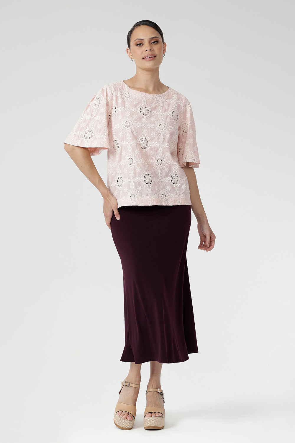 Featuring delicate ivory embroidery on a soft powdered pink base, it’s designed in a relaxed silhouette with a round neckline, topstitch detailing, and flared short sleeves finished with a subtle pleat.