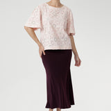 Featuring delicate ivory embroidery on a soft powdered pink base, it’s designed in a relaxed silhouette with a round neckline, topstitch detailing, and flared short sleeves finished with a subtle pleat.