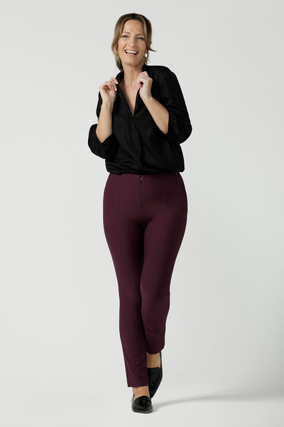 A size 10, forty plus woman wears slim leg, cropped length, stretch pants in Mulberry ponte jersey with a 3/4 sleeve pull-on black shirt. Made in Australia by Australian and New Zealand women's clothing brand, L&F, these easy care pants work for corporate wear and weekend wear.