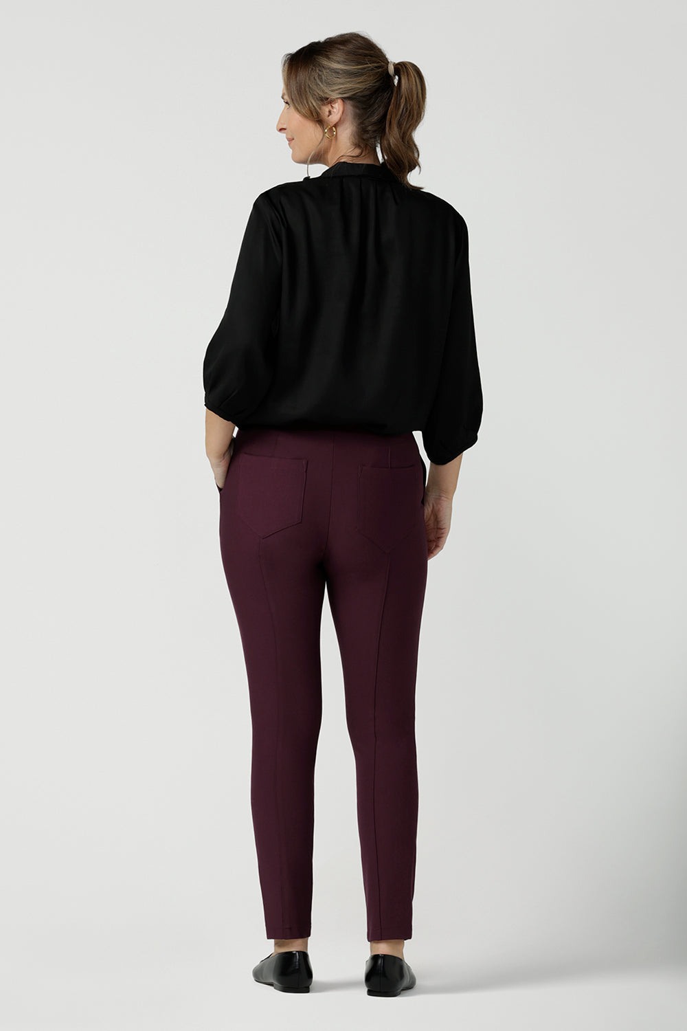 Back view of a size 10, forty plus woman wearing slim leg, cropped length, stretch pants in Mulberry ponte jersey and a 3/4 sleeve pull-on black shirt. Made in Australia by Australian and New Zealand women's clothing brand, L&F, these easy care pants work for corporate wear and weekend wear.