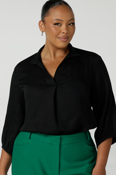 size 18 curvy woman wearing a pull-on black shirt with 3/4 sleeves in eco-friendly Tencel. The shirt is worn with emerald green pants for a classic work wear look. This black shirt is made in Australia for petite to plus size women.