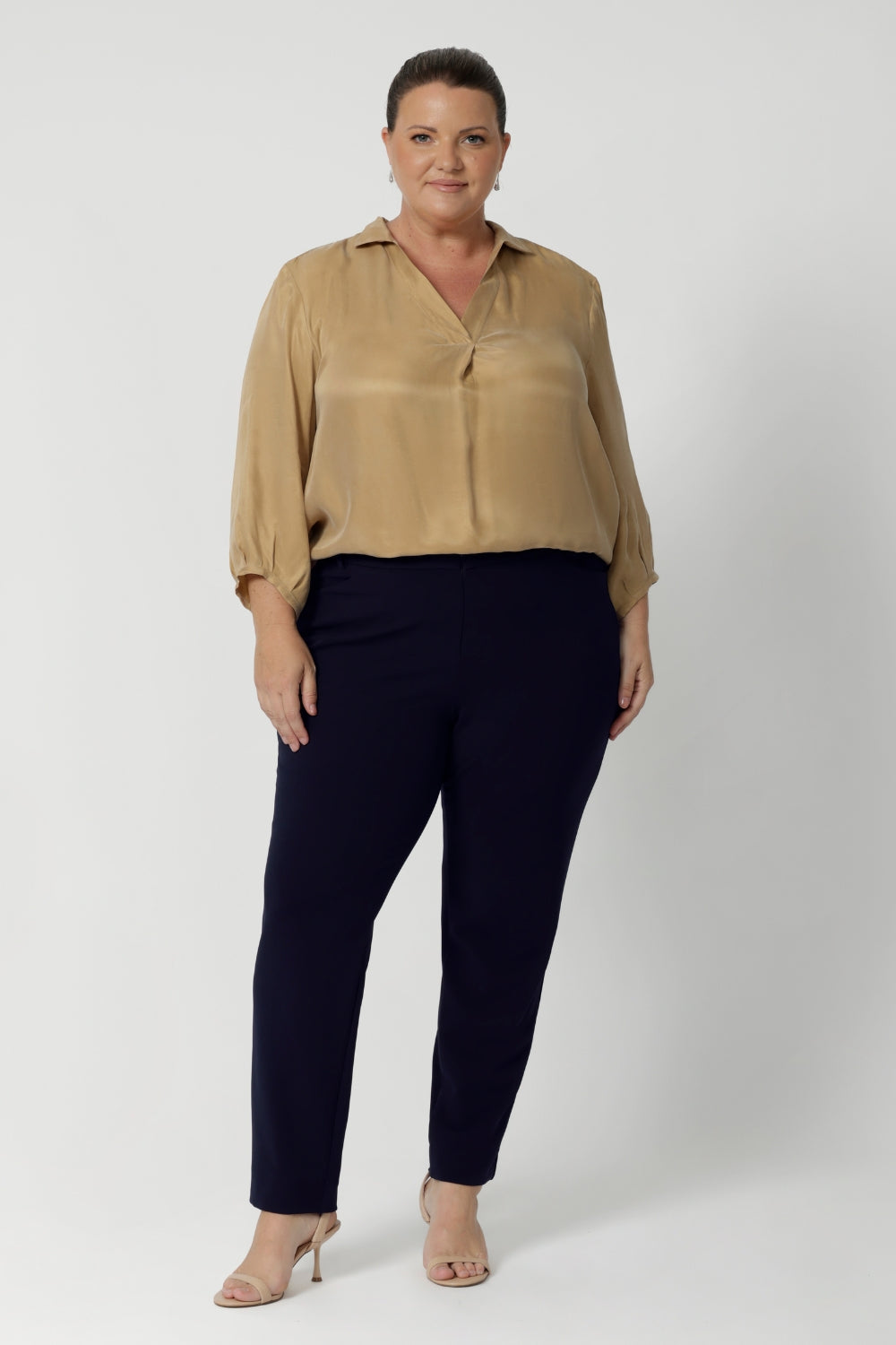 The shirttail hemline provides a relaxed yet polished finish, perfect for tucking into high-waisted trousers or skirts, or leaving out for a more casual, effortless look. Size 18 woman wears her soft blouse tucked into navy tapered leg pants and nude heels. Available in sizes 8-24.