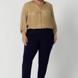 The shirttail hemline provides a relaxed yet polished finish, perfect for tucking into high-waisted trousers or skirts, or leaving out for a more casual, effortless look. Size 18 woman wears her soft blouse tucked into navy tapered leg pants and nude heels. Available in sizes 8-24.