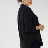 Side view of woman wearing Graphite coloured woven shirt with collar and tailored pleat with navy workwear pants. Made from sustainable Tencel fabric in Australia in sizes 8-24. 