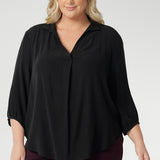 Plus size woman wearing woven shirt with collar and tailored pleat with wine coloured workwear pants. Made from sustainable Tencel fabric in Australia in sizes 8-24. 