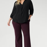 Plus size woman wears Graphite coloured woven shirt with collar and tailored pleat with wine work pants and black boots. Made from sustainable Tencel fabric in Australia for petite and plus size woman sizes 8-24. 