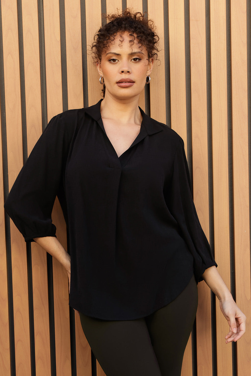 Plus size woman wears Graphite coloured woven shirt with collar and tailored pleat with wine work pants and black boots. Made from sustainable Tencel fabric in Australia for petite and plus size woman sizes 8-24. 