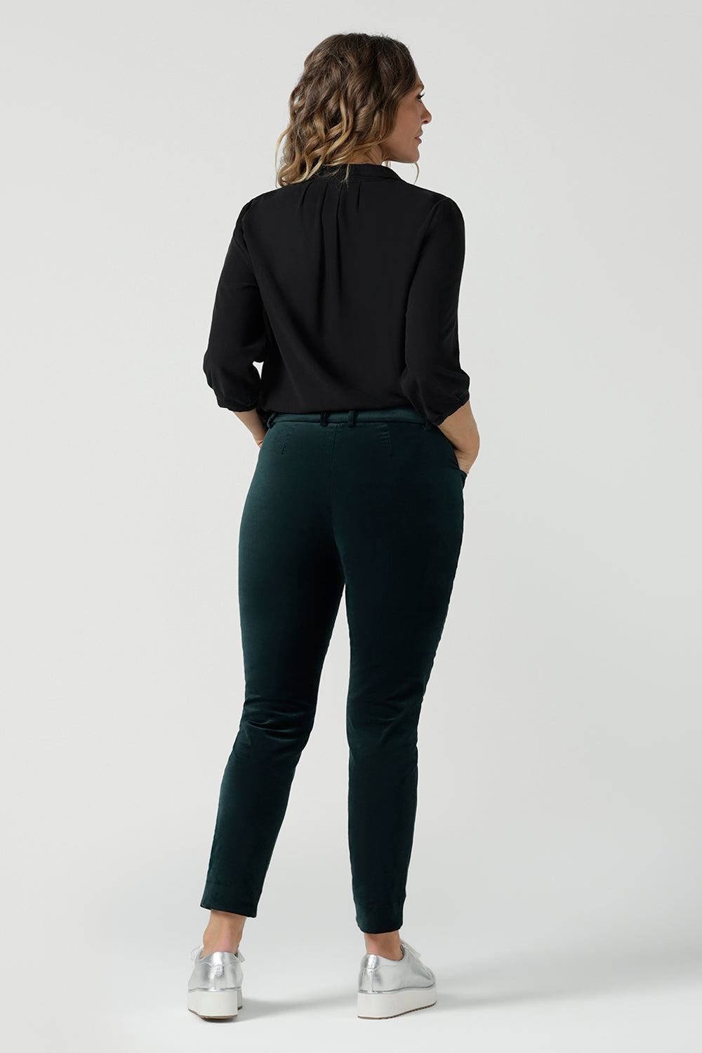 Back view of a woman wears the Arley Shirt in Graphite Tencel. A woven shirt with collar and tailored pleat front. Made from sustainable tencel fabric. Made in Australia for women petite to plus size 8-24. Styled back with Velveteen pants.