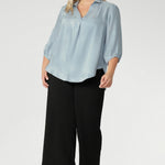 Crafted in an easy-care woven fabric and made in Australia for women across Australia and New Zealand in sizes 8 to 24. The Arley Shirt delivers comfort and easy elevated dressing. Plus size woman wears her Arley Shirt over black work pants. 