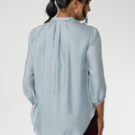 Semi-fitted through the body, it features a classic collar neckline and subtle tuck details below the back neckline, adding gentle structure without compromising comfort. The ¾ length sleeves fall softly and are finished with narrow bound hems, bringing a refined finish to a relaxed shape. 