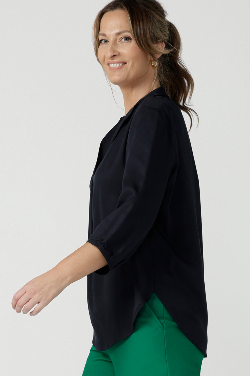 size 10  woman wearing a pull-on Midnight navy  shirt with 3/4. Made in Tencel fabric, the Midnight navy shirt is lightweight, breathable and eco-conscious. Worn with emerald green pants, this shirt is great for casual wear as well as work. The shirt is Australian made for petite to plus size women.