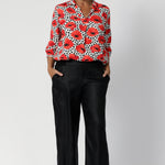 Whether you’re dressing for the office or a weekend brunch, this top delivers both style and comfort with an effortlessly chic vibe. Over 40's woman wears printed shirt with black linen pants and black heels.