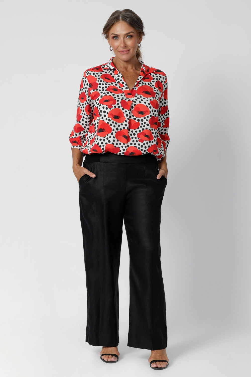 Whether you’re dressing for the office or a weekend brunch, this top delivers both style and comfort with an effortlessly chic vibe. Over 40's woman wears printed shirt with black linen pants and black heels.