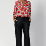 Whether you’re dressing for the office or a weekend brunch, this top delivers both style and comfort with an effortlessly chic vibe. Over 40's woman wears printed shirt with black linen pants and black heels.