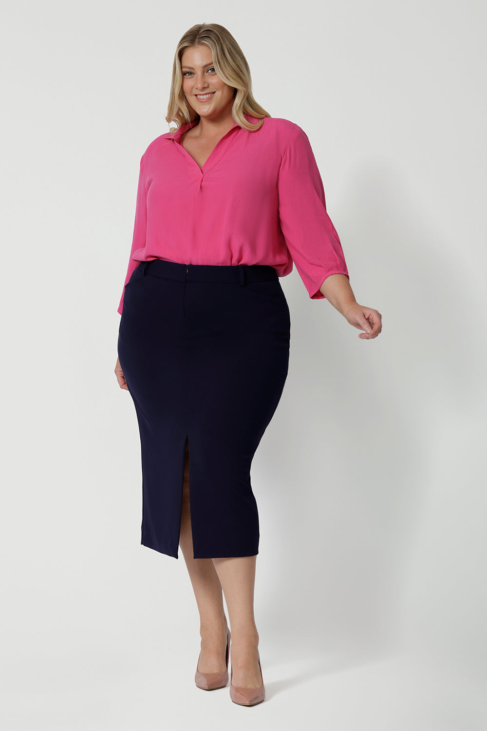 Full body front view of 40 year old plus sized woman wearing a midi length work skirt. This workwear skirt is navy in colour and made of good quality scube crepe fabric. This skirt has an above the knee slit for comfort and mobility. Perfect skirt for an office or corporate setting. 3/4 length skirt is Australia made by New Zealand and Australian women. Leina & Fleur is a clothing company for woman that stock sizes from 8 to 24. Shop this work skirt in plus sizes and petite sizes. 