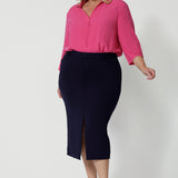 Showing a great work shirt for plus size women, a curvy woman wears a pink tencel fabric shirt in size 18. Workwear shirt displays 3/4 length sleeves tucked into a navy skirt. This collared shirt is made from tencel fabric made in Australia by Australian and New Zealand women. Woman’s clothing brand Leina & Fleur stock sizes from 8 to 24 including plus sizes and petite sizes.