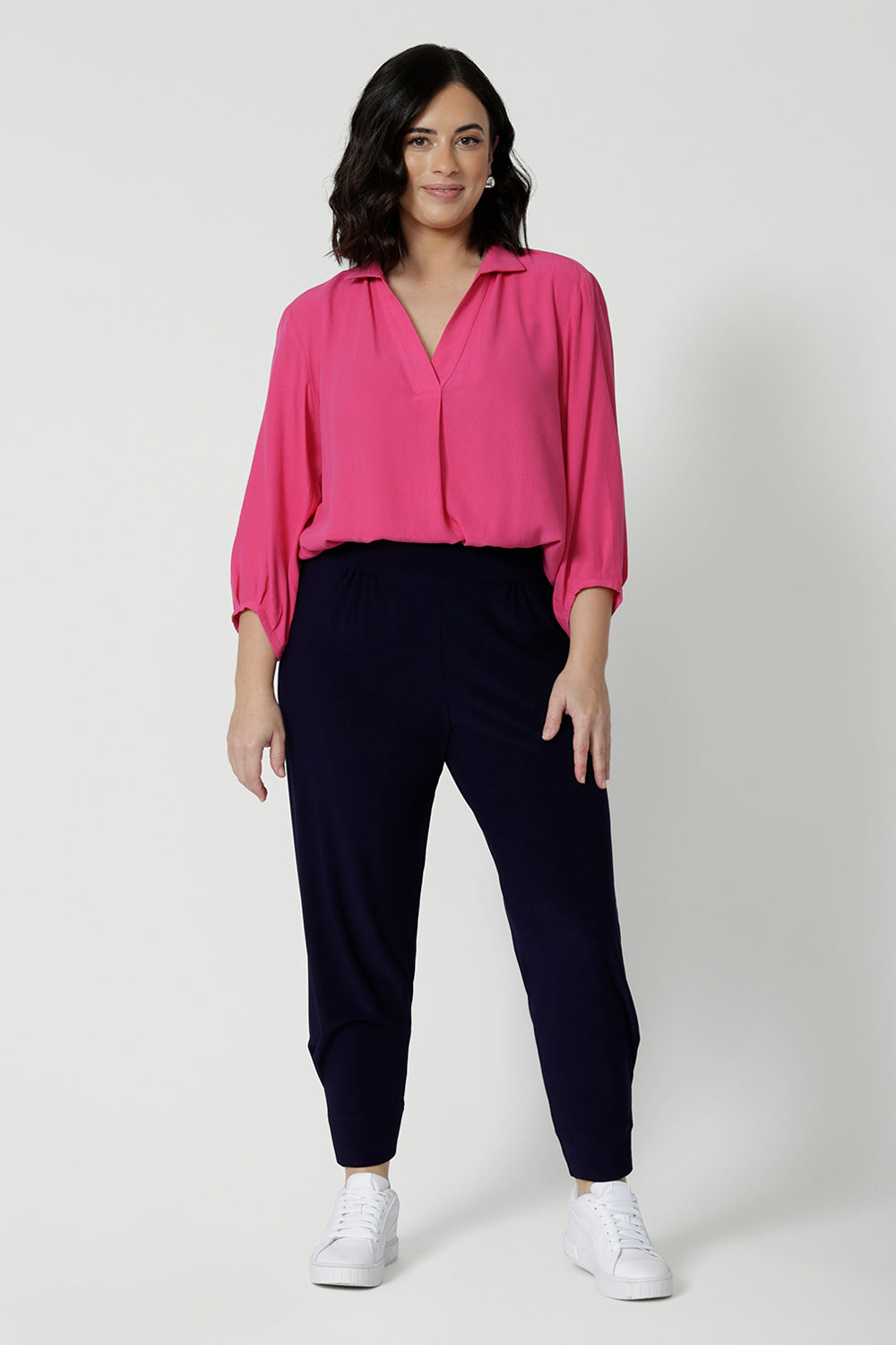 Showing a good work shirt for petite women, a size 12 woman wears a pink tencel fabric shirt tucked into black pants. Shirt has 3/4 sleeves, v neck and collar. This tencel fabric shirt is breathable and Australian made. Made by woman in Australia and New Zealand. Leina and Fleur is a woman’s workwear clothing brand that has sizes ranging from 8 to 24 including plus sizes and petite sizes. 