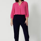 Showing a good work shirt for petite women, a size 12 woman wears a pink tencel fabric shirt tucked into black pants. Shirt has 3/4 sleeves, v neck and collar. This tencel fabric shirt is breathable and Australian made. Made by woman in Australia and New Zealand. Leina and Fleur is a woman’s workwear clothing brand that has sizes ranging from 8 to 24 including plus sizes and petite sizes. 