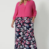 Full length body shot of plus sized woman wearing floral wide legged pants. The pant is designed with floral fabric combining white and pink on navy base. Easy care dry touch jersey fabric, pants designed in Australia by Australian and New Zealand women. Leina & Fleur is a fashion retailer that stock sizes from 8 to 24 with plus and petite sizes available. 