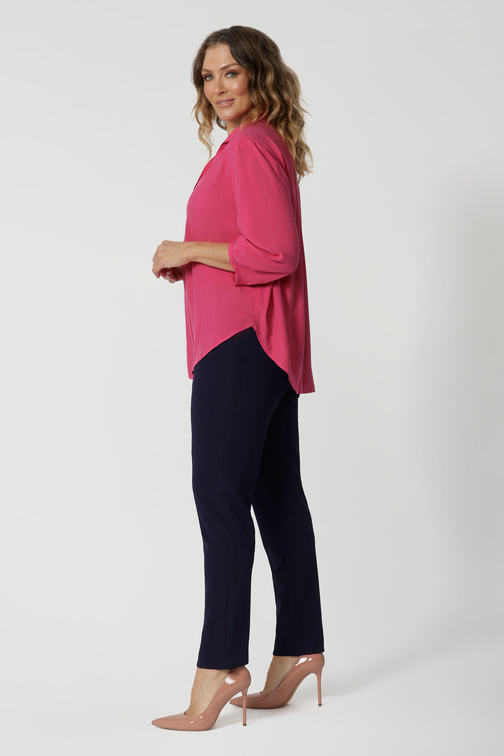 Side view of an over 40 year old woman wearing a shirt in a pink tencel fabric. This workwear shirt is for women on the go, made from Australian manufactured tencel fabric in the colour pink. Made in Australia by Australian and New Zealand women. Leina & Fleur is women's clothes brand with sizes that range from 8 to 24. Plus sizes and petite sizes are available.