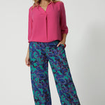 Full body front image of an over 40 woman, wearing long wide pants with an abstract pattern. Made of easy to care satin rayon fabric displaying aqua blue, navy and pink colours. This Australian made product was made by woman in Australia and New Zealand. Leina & Fleur is a woman’s online clothing brand that has sizes ranging from 8 to 24 including plus sizes and petite sizes. 