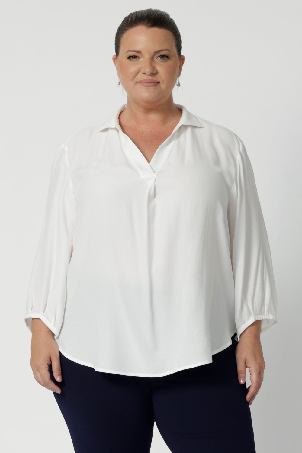 Plus size women wears tailored blouse in vanilla with 3/4 sleeves and collar neckline. Light weight blouse made in sustainable Tencel fabric. Soft and easy care workwear for women for petite to plus size 8-24. Made in Australia. 