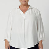 Plus size women wears tailored blouse in vanilla with 3/4 sleeves and collar neckline. Light weight blouse made in sustainable Tencel fabric. Soft and easy care workwear for women for petite to plus size 8-24. Made in Australia. 