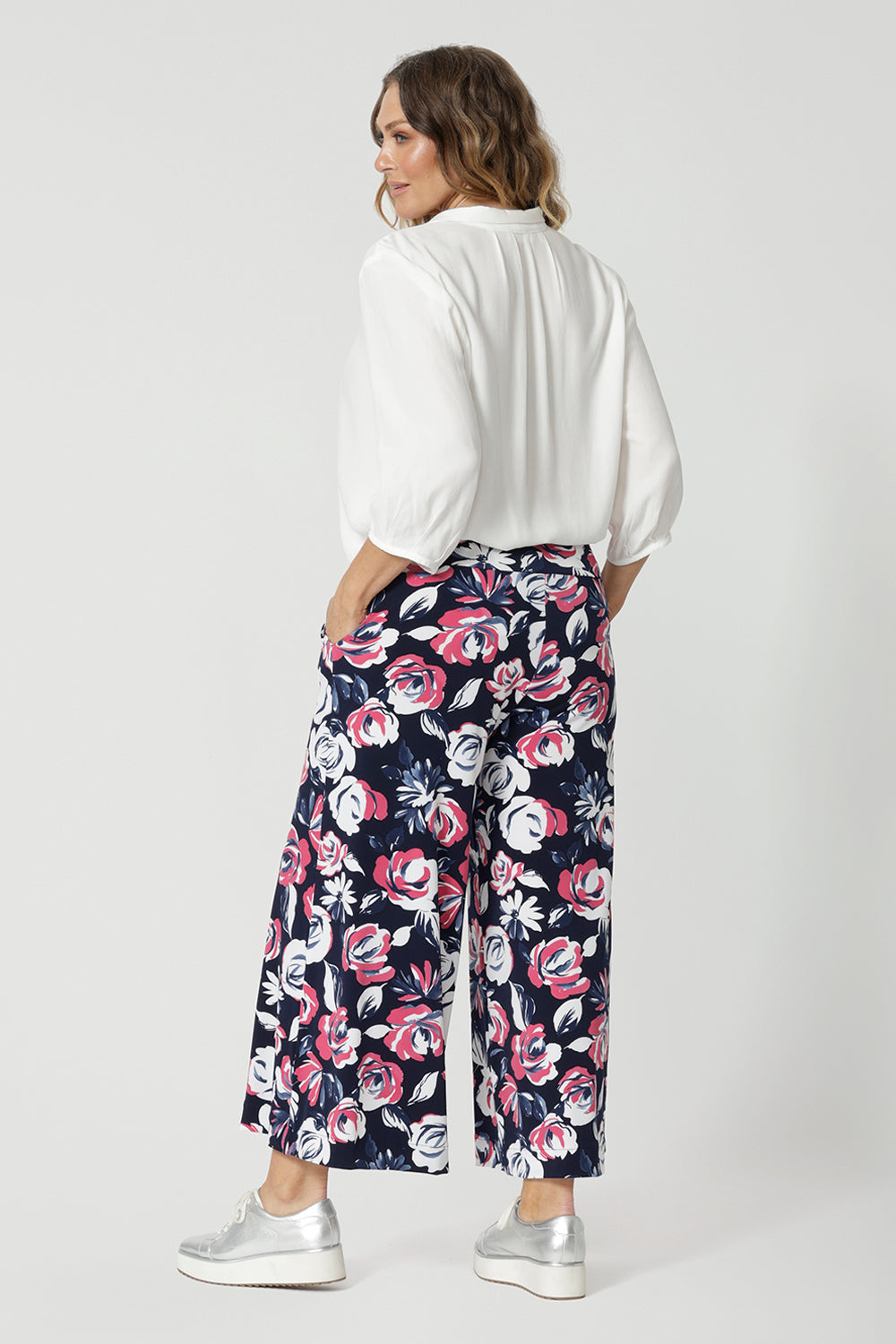 Back view of 40 year old woman wearing a breathable fabric pant made of dry touch jersey fabric. Floral pattern shirt has many colours such as white, pink and blue. This comfortable work wear pant is great for both casual wear and dressed up for an occasion. These easy care pants are made in Australia by Australian and New Zealand women. Leina & Fleur is a woman’s fashion label that stocks sizes from 8 to 24. Shop this comfortable pant in plus size and petite sizes. 