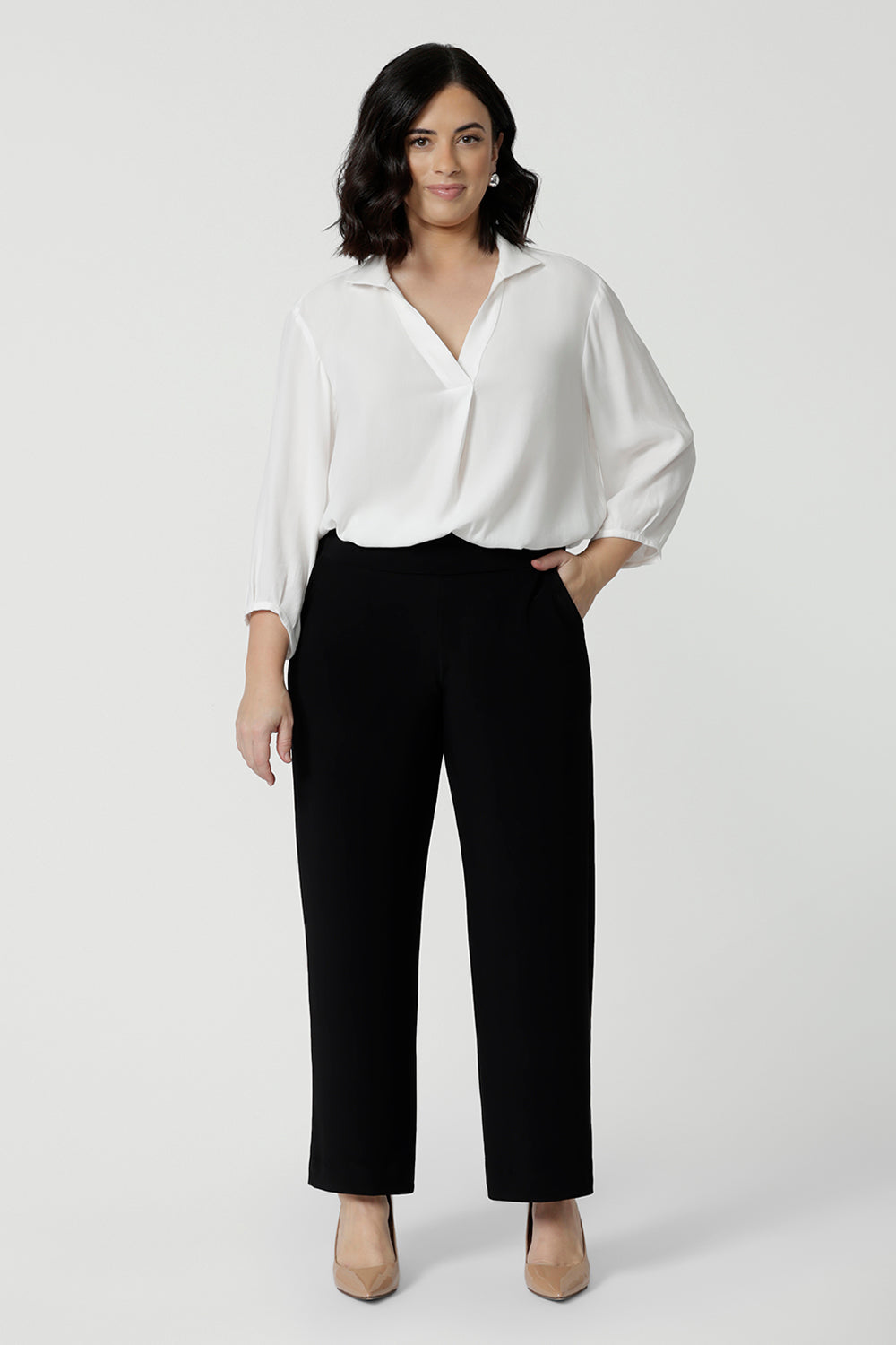 A petite height woman wears black work pants in petite length with a white tencel shirt. Great pants for short women, these Australian-made pull-on trousers are available in sizes 8 to 24, petite to plus sizes.