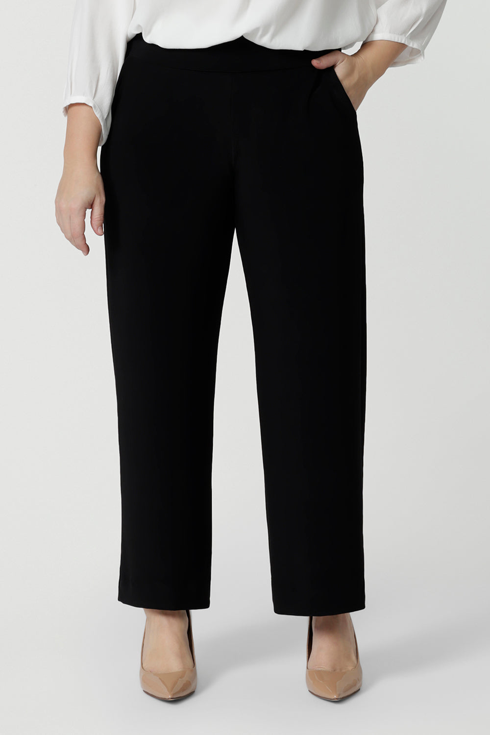 A petite height woman wears black work pants in petite length with a white tencel shirt. Great pants for short women, these Australian-made pull-on trousers are available in sizes 8 to 24, petite to plus sizes.