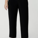 A petite height woman wears black work pants in petite length with a white tencel shirt. Great pants for short women, these Australian-made pull-on trousers are available in sizes 8 to 24, petite to plus sizes.