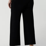 A petite height woman wears black work pants in petite length with a white tencel shirt. Great pants for short women, these Australian-made pull-on trousers are available in sizes 8 to 24, petite to plus sizes.