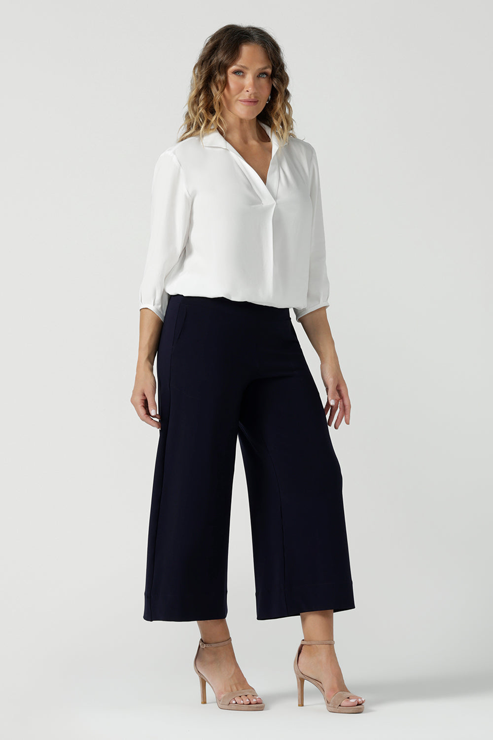 A size 10 woman wears the Arley Shirt in in Vanilla Tencel. A soft tailored shirt with 3/4 sleeves and collar neckline. Made in sustainable tencel fabric. Soft and easy care workwear for women for petite to plus size 8-24. Made in Australia. Styled back with a Bradley culotte in black. 