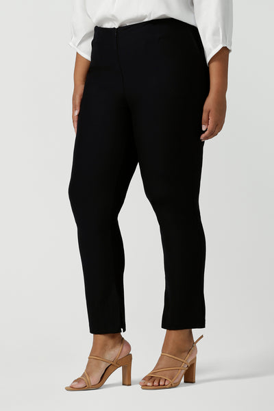 Close up of a fuller figure woman wearing mid-rise, slim leg navy pants by Australian and New Zealand women's clothing label, L&F. These skinny workwear trousers have a concealed zip fastening and side pockets. Worn with a 3/4 sleeve white women's shirt. Shop these navy workwear pants in an inclusive size range of 8 to 24.