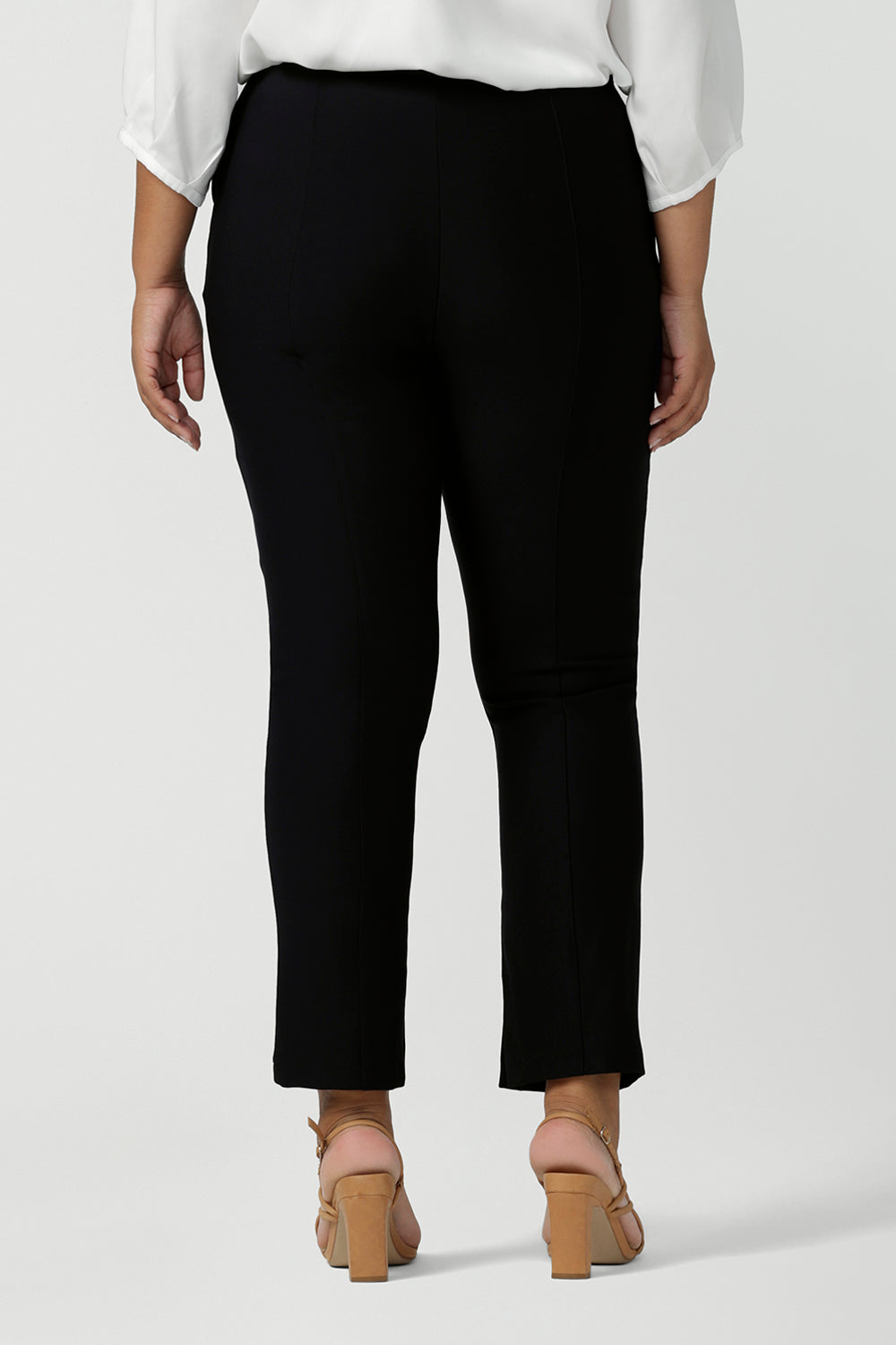 Back view of a fuller figure woman wearing mid-rise, slim leg navy pants by Australian and New Zealand women's clothing label, L&F. These skinny workwear trousers have a concealed zip fastening and side pockets. Worn with a 3/4 sleeve white women's shirt. Shop these navy workwear pants in an inclusive size range of 8 to 24.