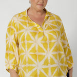 Plus sized woman wears bright yellow shirt that features a simple design that adds a touch of modern flair. Crafted from eco-friendly tencel fabric, it offers a soft and breathable feel, perfect for both comfort and sustainability. Available in size 8-24.