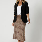 Size 12 model has paired skirt with black Merit Blazer and brown sandal for an elevated work look. The Asher Skirt is a midi length with bias cut hemline giving the skirt movement and elegant flare. Available in sizes 8-24.