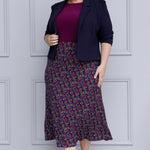 Size 18 woman wears workwear midi skirt paired with magenta top and navy jacket for an elevated workwear look. Crafted on floral dry touch fabric, this skirt features a bias-cut design that drapes beautifully, creating a flattering, easy fluid silhouette. Available in sizes 8-24.