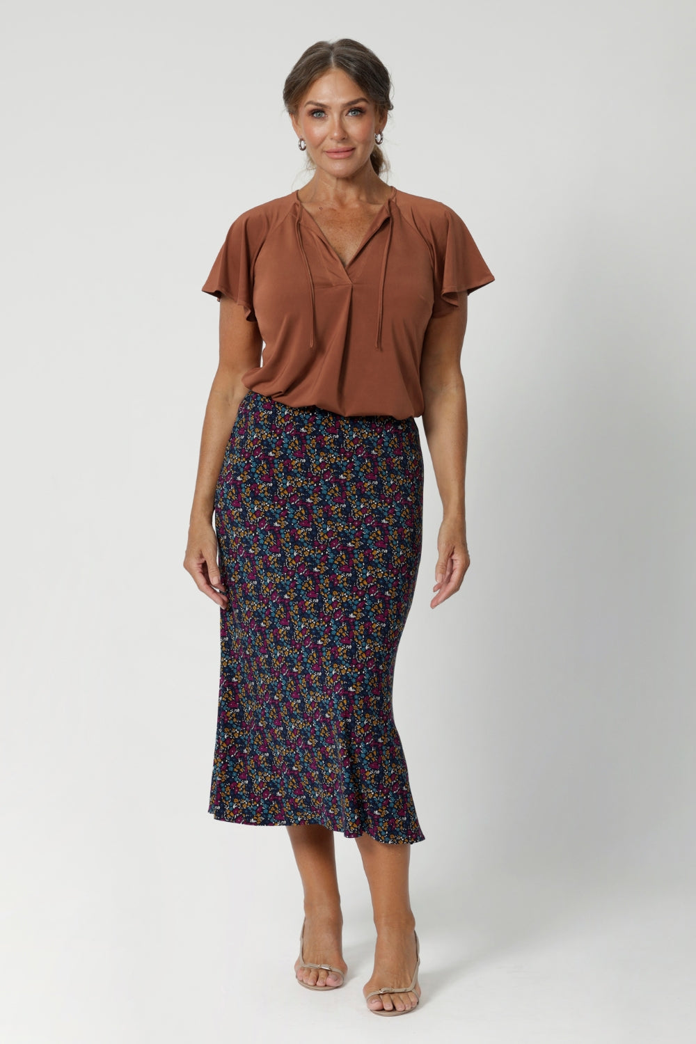 A sleek, sophisticated staple design for both work and travel. Size 12 woman wears clay coloured top with midi skirt and nude heel. Made from easy care dry touch jersey, that is wrinkle resistant. Available in sizes 8-24. 