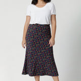 Petite height model wears midi skirt that offers a lightweight feel that's perfect for all-day comfort. Size 10 woman wears travel ready skirt with white t-shirt and platform shoes.